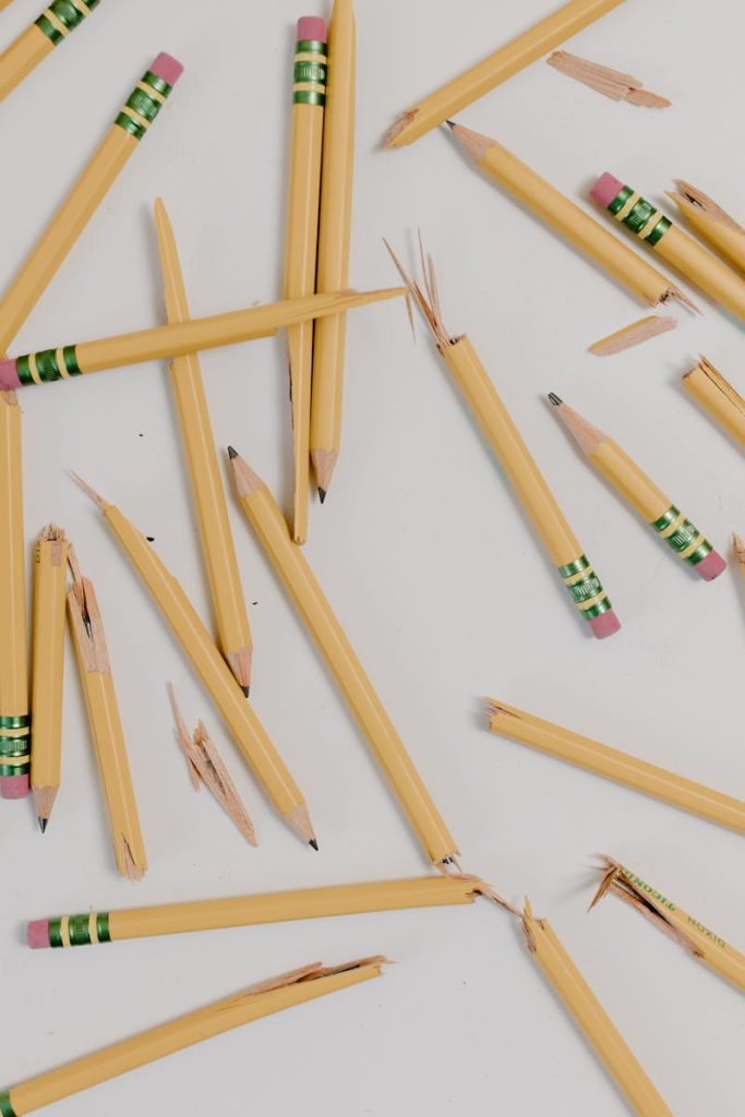 A flat lay of broken pencils scattered on a white background.